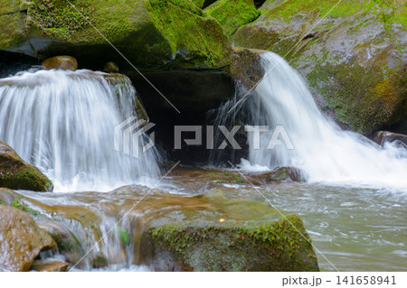 small waterfall closeup. beautiful cascade on the water stream with mossy rock small waterfall closeup. beautiful cascade on the water stream with mossy rock 141658941