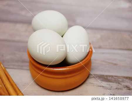 Fresh duck eggs in clay bowl on rustic wooden table. Organic farm produce, healthy natural food ingredient for cooking, baking and nutritious meals. 141658977