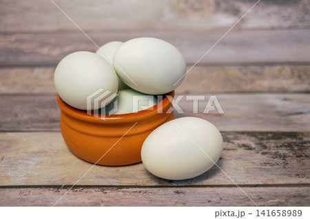 Fresh duck eggs in clay bowl on rustic wooden table. Organic farm produce, healthy natural food ingredient for cooking, baking and nutritious meals. 141658989