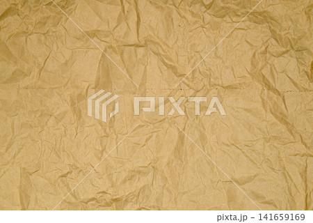 horizontally oriented crumpled beige kraft paper sheet covered in network of small creases 141659169