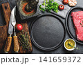 Raw fresh premium meat steak beef tenderloin, herbs and spices around frying pan plate, copy space 141659372