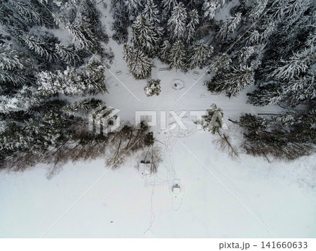 Aerial winter clearing with firepit and huts in boreal forest Aerial winter clearing with firepit and huts in boreal forest 141660633