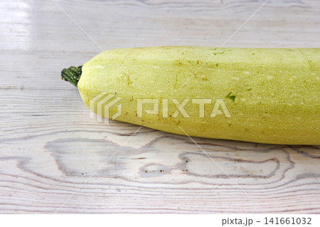 Whole pale green zucchini on light wooden table. Minimal composition. Selective focus Whole pale green zucchini on light wooden table. Minimal composition. Selective focus 141661032
