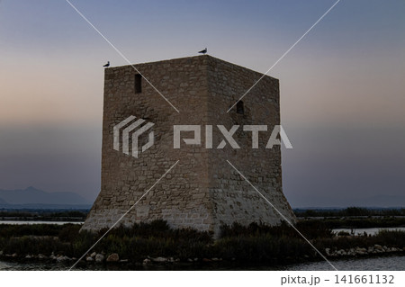 Historic Tamarit watchtower stands in Santa Pola surrounded by salt flats at dusk with a view of Spanish heritage and coastal defense history 141661132