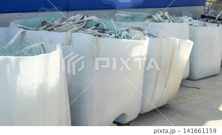 White industrial storage bins filled with green fishing nets at marine harbor on sunny day White industrial storage bins filled with green fishing nets at marine harbor on sunny day 141661159