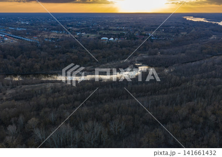 Aerial sunset over river and leafless forest near Warsaw, Mazovia Aerial sunset over river and leafless forest near Warsaw, Mazovia 141661432
