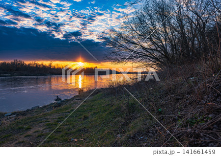 Vistula River near Warsaw at dusk with sunset and bare riverside trees Vistula River near Warsaw at dusk with sunset and bare riverside trees 141661459