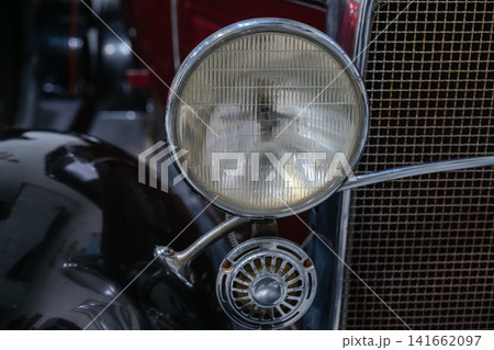Detailed close up of a vintage headlight and horn mounted on a classic automobile. The image highlights antique automotive craftsmanship and chrome accents. 141662097