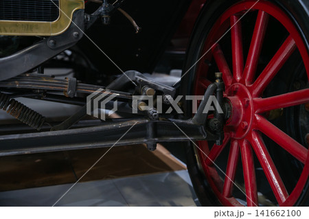 A detailed close up of a vintage automobile wheel and chassis mechanism in a museum exhibit. The image emphasizes historic transportation technology and craftsmanship. 141662100