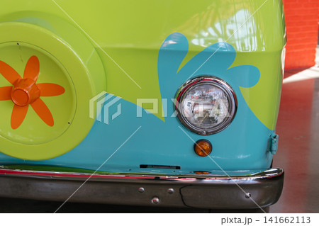 A close up view highlights the colorful front styling of a retro themed van. Bright colors and floral graphics create a playful vintage appearance. A close up view highlights the colorful front styling of a retro themed van. Bright colors and floral graphics create a playful vintage appearance. 141662113