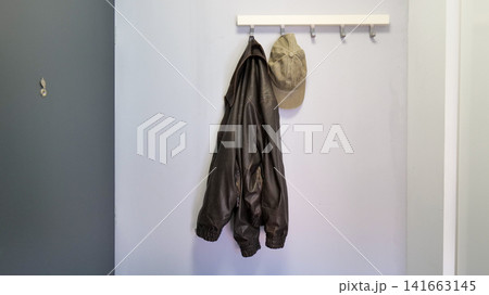 Jacket and Cap Hanging on a Hook Rack in an Entryway 141663145