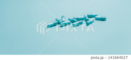 Blue antibiotic capsule pills on pastel blue background. Pharmacy web banner. Antibiotic drug resistance. Antimicrobial capsule pills with space. Health budget and policy. Pharmaceutical industry. Blue antibiotic capsule pills on pastel blue background. Pharmacy web banner. Antibiotic drug resistance. Antimicrobial capsule pills with space. Health budget and policy. Pharmaceutical industry. 141664027