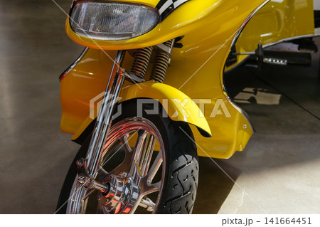 A close-up view of a chrome front wheel on a custom three-wheel vehicle. The image emphasizes engineering, polished metal surfaces, and performance styling. A close-up view of a chrome front wheel on a custom three-wheel vehicle. The image emphasizes engineering, polished metal surfaces, and performance styling. 141664451