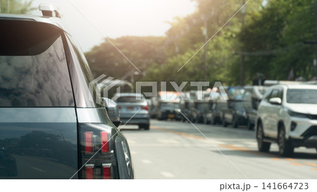 Rear view shot of cars stuck in heavy traffic during the daytime. Showing vehicles queuing on a city street. Cars are parked on both sides of the road leaving the middle lane empty. Rear view shot of cars stuck in heavy traffic during the daytime. Showing vehicles queuing on a city street. Cars are parked on both sides of the road leaving the middle lane empty. 141664723