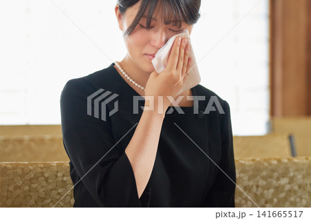 ハンカチをあてて涙を拭う喪服の若い女性 ハンカチをあてて涙を拭う喪服の若い女性 141665517