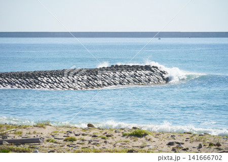 防波堤の消波ブロックに当たり白く弾ける海の波 141666702