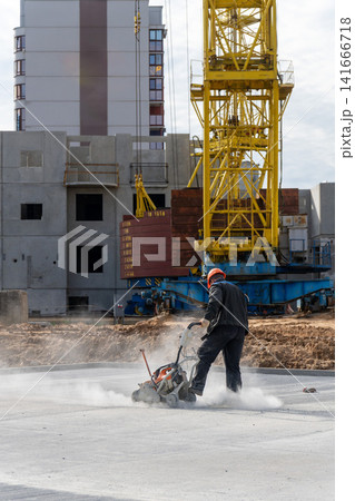 A worker in an orange helmet cuts concrete A worker in an orange helmet cuts concrete 141666718