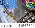 Rustic handmade sewing and textile craft composition with lace colorful threads scissors buttons beads and copy space on wooden background flat lay style 141667294