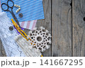 Handmade crochet snowflake ornament with lace colorful threads scissors and sewing accessories on rustic wooden background winter craft flat lay composition 141667295