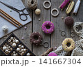 Sewing and knitting tools flat lay with donut pincushions embroidery hoop scissors yarn beads and lace on rustic wooden table cozy handmade craft background 141667304