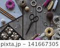 Handmade sewing and knitting workspace with colorful pincushions embroidery hoop lace scissors yarn and crochet accessories on wooden background flat lay style 141667305
