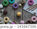 Handmade knitting and sewing frame composition with colorful donut pincushions yarn scissors lace and embroidery accessories on wooden table flat lay 141667306