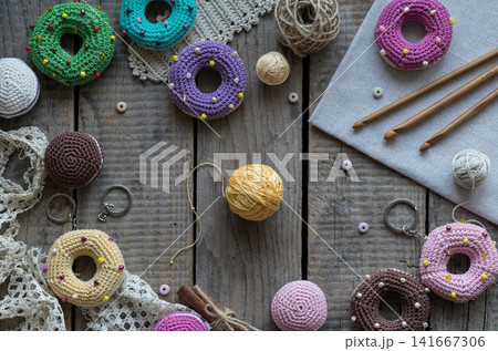 Handmade knitting and sewing frame composition with colorful donut pincushions yarn scissors lace and embroidery accessories on wooden table flat lay Handmade knitting and sewing frame composition with colorful donut pincushions yarn scissors lace and embroidery accessories on wooden table flat lay 141667306