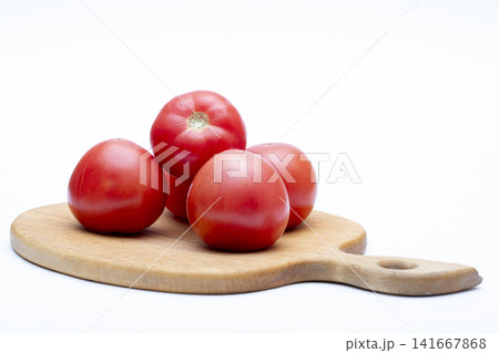 Ripe red tomatoes on a wooden board against a white background Ripe red tomatoes on a wooden board against a white background 141667868