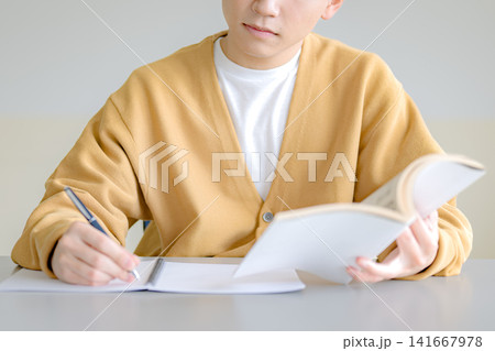 本を読みながらメモを取る男性、読書習慣のイメージ 本を読みながらメモを取る男性、読書習慣のイメージ 141667978