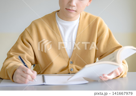 本とノートを使い学習する男性、資格勉強のイメージ 本とノートを使い学習する男性、資格勉強のイメージ 141667979