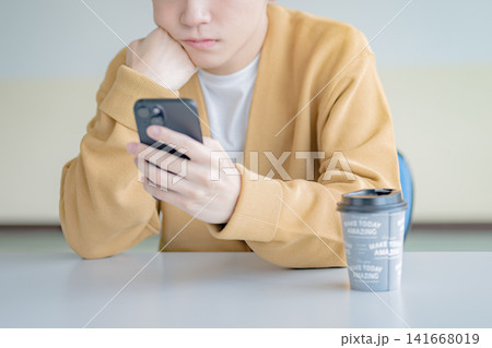 スマホを見る男性、休憩中の暇つぶしイメージ スマホを見る男性、休憩中の暇つぶしイメージ 141668019