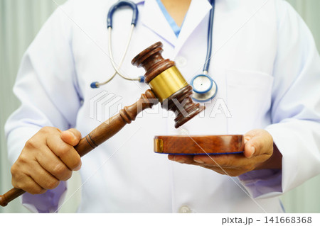 Asian doctor holding court hammer for and crime law justice, forensic medicine. Asian doctor holding court hammer for and crime law justice, forensic medicine. 141668368