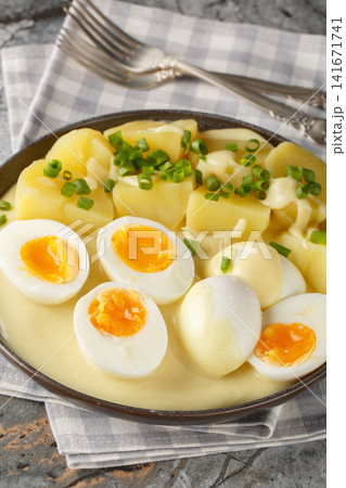 Senfeier German eggs in mustard sauce with a side dish of boiled potatoes close-up in a plate. Vertical Senfeier German eggs in mustard sauce with a side dish of boiled potatoes close-up in a plate. Vertical 141671741
