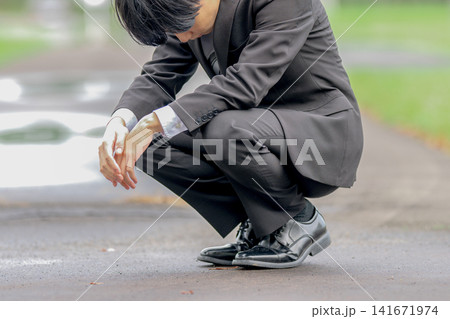 地面を見つめるスーツ姿の男性、脱力・放心のイメージ 地面を見つめるスーツ姿の男性、脱力・放心のイメージ 141671974