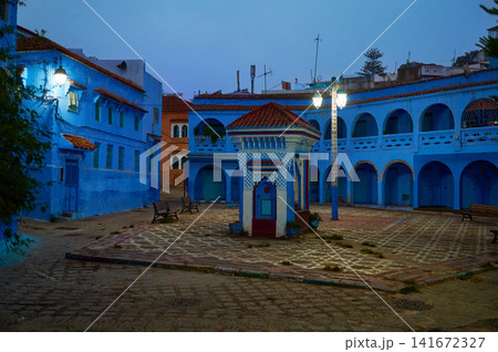 Blue medina square in Moroccan town at dusk with traditional architecture and tiled fountain Blue medina square in Moroccan town at dusk with traditional architecture and tiled fountain 141672327