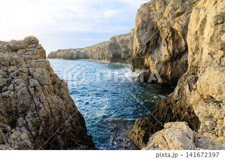 Dramatic rock formations create a natural grotto along a wild coastline bathed in warm sunshine Dramatic rock formations create a natural grotto along a wild coastline bathed in warm sunshine 141672397