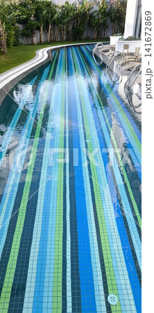 Modern swimming pool with colorful mosaics and sun loungers nearby 141672869