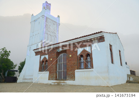 White mosque tower and brick building in misty mountain village at dawn White mosque tower and brick building in misty mountain village at dawn 141673194