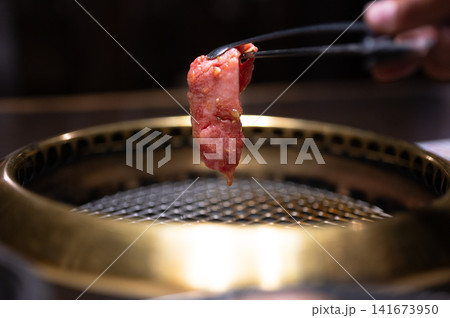 焼肉の肉をトングでつかむ様子、炭火焼きのイメージ 焼肉の肉をトングでつかむ様子、炭火焼きのイメージ 141673950