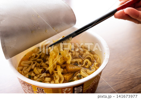 カップ麺を箸で持ち上げる様子、インスタントラーメンのイメージ カップ麺を箸で持ち上げる様子、インスタントラーメンのイメージ 141673977
