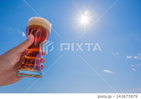 青空にビールを掲げる様子、乾杯のイメージ 青空にビールを掲げる様子、乾杯のイメージ 141673979