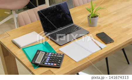 Modern home office workspace setup for freelance or study. Laptop, calculator, notebook, document folder. Remote Accounting, Home Bookkeeping. Wooden desk layout. Financial Planning. Work Life Balance Modern home office workspace setup for freelance or study. Laptop, calculator, notebook, document folder. Remote Accounting, Home Bookkeeping. Wooden desk layout. Financial Planning. Work Life Balance 141674313