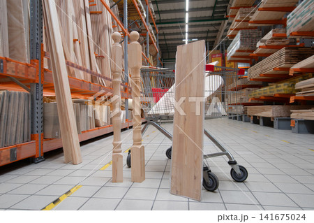 Shopping for wood supplies in a hardware store during the daytime with a shopping cart and lumber 141675024