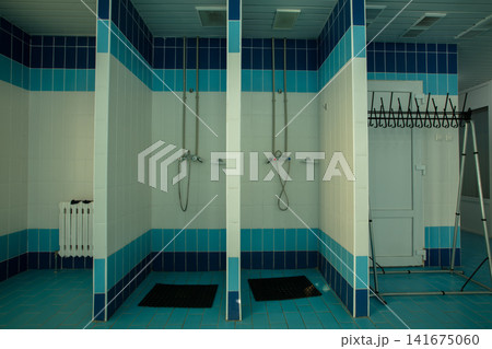 Shower area in changing room of a sports facility with clean tiles and simple design Shower area in changing room of a sports facility with clean tiles and simple design 141675060