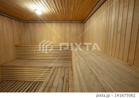 Wooden sauna interior with benches and lighting in a relaxation space 141675062