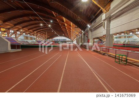 Indoor running track located in a sports facility with wooden beams and red lanes for athletics training and events Indoor running track located in a sports facility with wooden beams and red lanes for athletics training and events 141675069