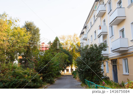 Residential neighborhood with lush greenery and apartment buildings during daylight in early autumn Residential neighborhood with lush greenery and apartment buildings during daylight in early autumn 141675084
