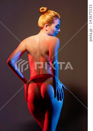Female figure in red underwear under dramatic red and blue studio lighting Female figure in red underwear under dramatic red and blue studio lighting 141675533