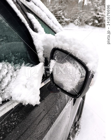 Car side mirror and window covered in a thick layer of snow and ice after a snowfall. Car side mirror and window covered in a thick layer of snow and ice after a snowfall. 141676696
