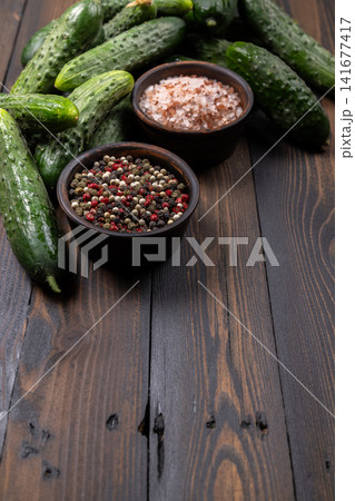 Pickling cucumbers, mixed peppercorns and pink salt on wood Pickling cucumbers, mixed peppercorns and pink salt on wood 141677417